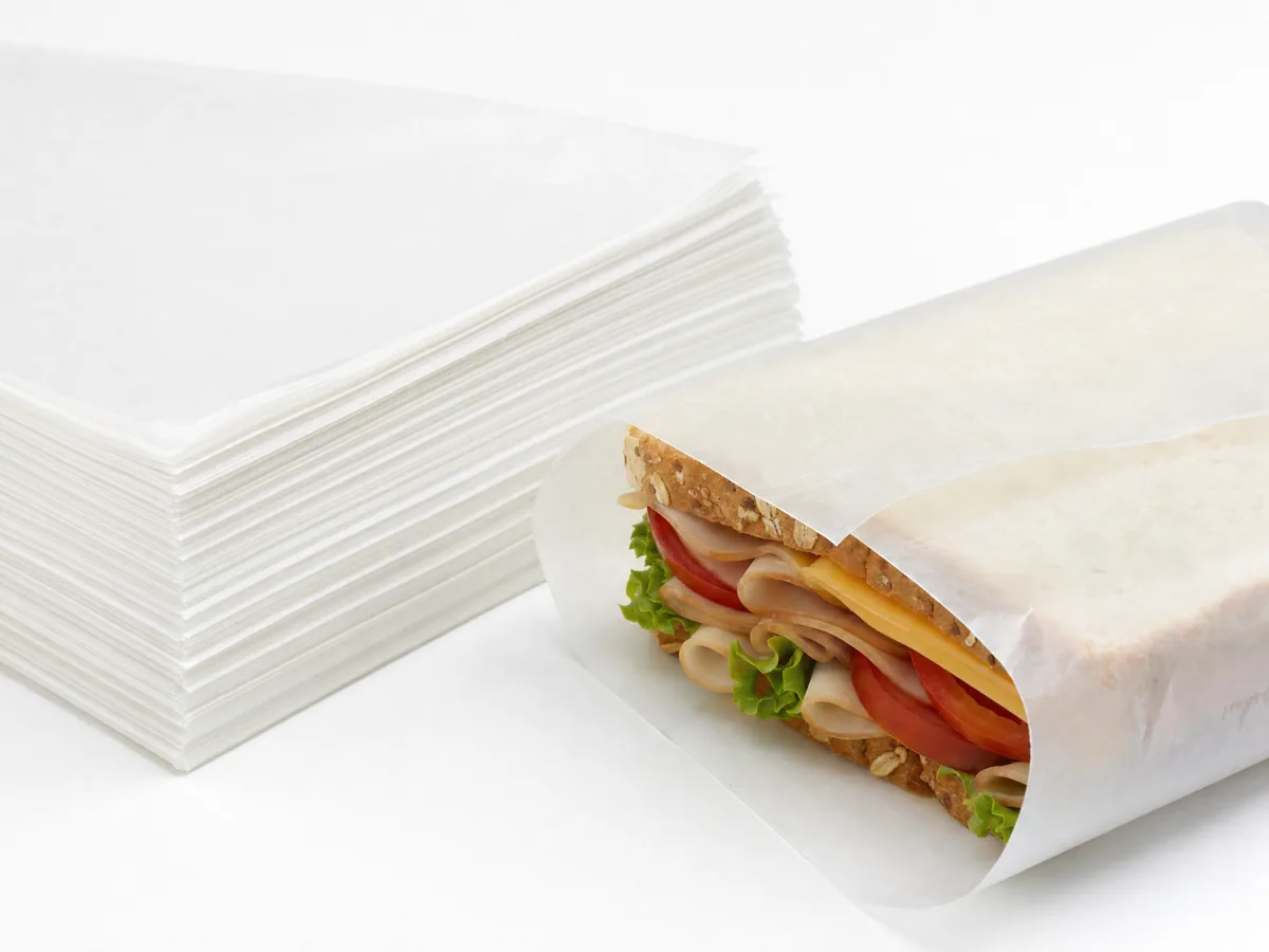 Custom logo-printed dry wax deli paper wrapped around a sandwich, CupsPak custom sandwich paper