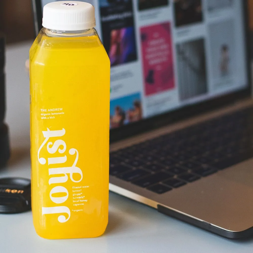 Branded screen-printed PET juice bottle in real use on a desk, CupsPak custom bottles