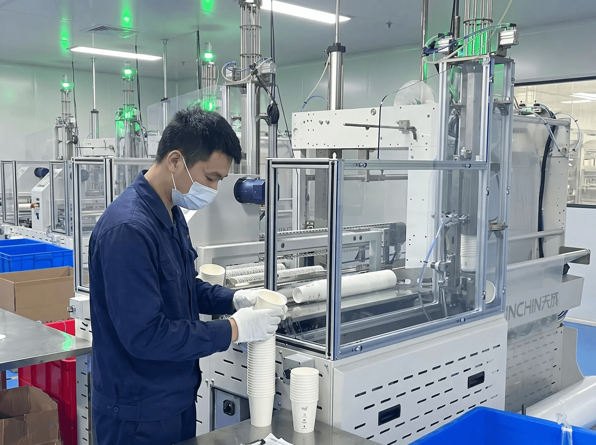 CupsPak quality control — technician inspecting paper cups on high-speed production line